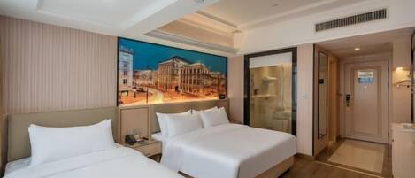 A hotel room with two beds, a large painting on the wall, a built-in desk, and a separate bathroom.