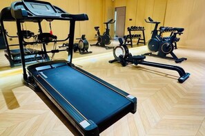 A gym with a treadmill, stationary bikes, and elliptical machines.