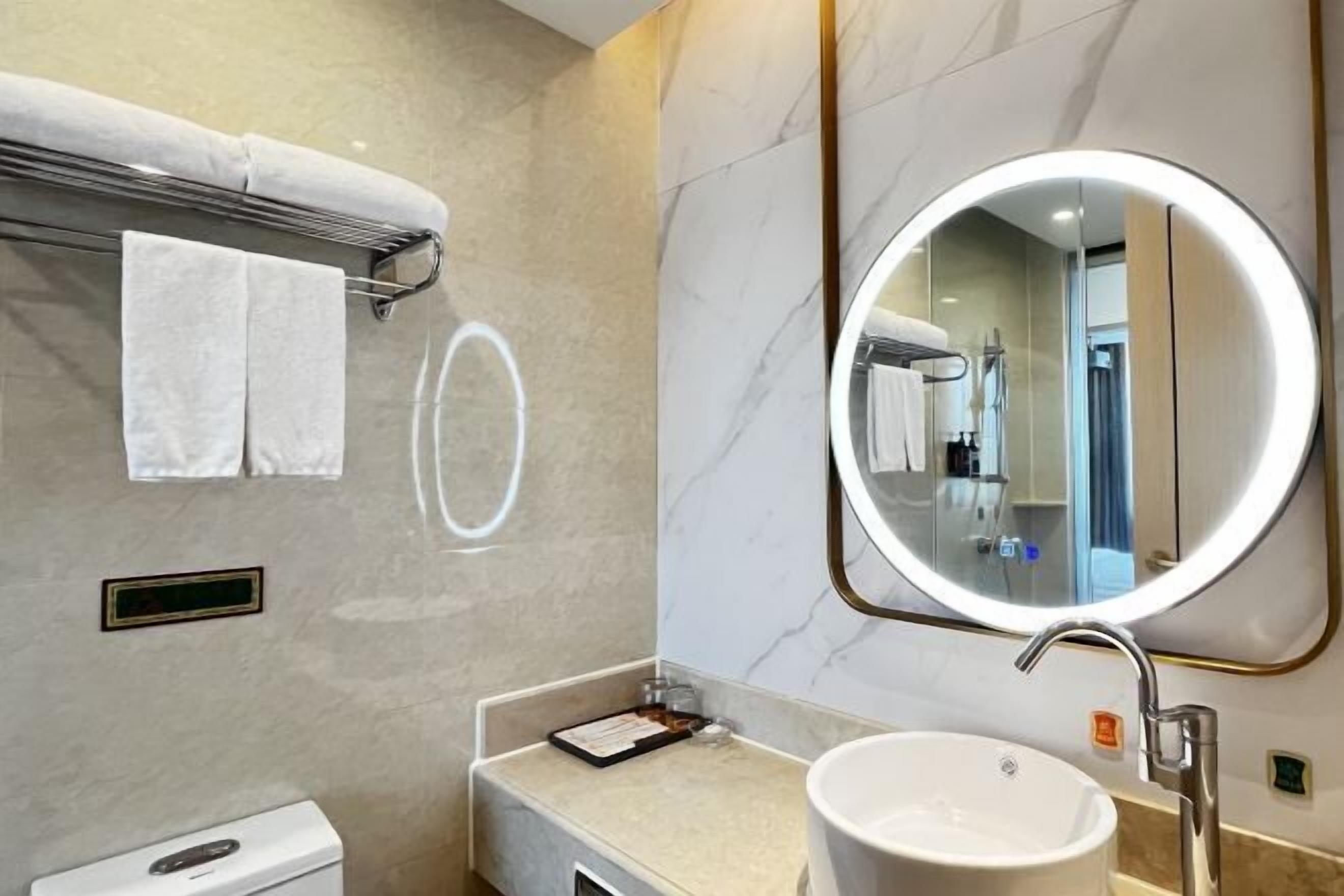 Ein modernes Badezimmer mit rundem Spiegel, Waschbecken und Handtuchhalter.