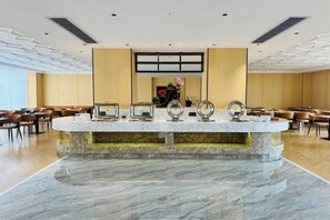 A hotel lobby with a marble reception desk, seating area, and a large window.