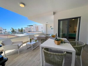 A modern balcony with a dining table, chairs, and a potted plant. - Incredibly Beautiful condo just steps to the beach (Punta Cana)