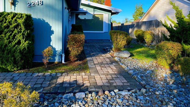A house with a number 2248 on the side, a chimney, and a paved driveway leading to the front door.
