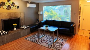 A living room with a fireplace, a sofa, a coffee table, and a large window with a view.