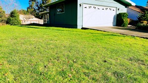 A single-story house with a garage, a well-maintained lawn, and a clear blue sky.