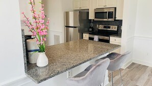 Una cocina moderna con encimeras de granito, electrodomésticos de acero inoxidable y armarios blancos.