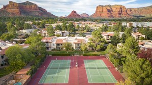 Ein Tennisplatz, umgeben von Wohnhäusern, mit einer Bergkulisse im Hintergrund.
