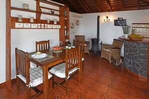 A dining area with a wooden table set for two, surrounded by wicker chairs. - Casa Antonia en Tijarafe (Tijarafe)
