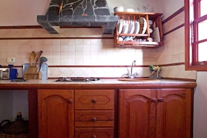 A kitchen with wooden cabinets, a stone range hood, and a dish rack. - Casa Antonia en Tijarafe (Tijarafe)