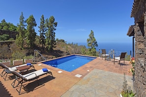 A rectangular pool with a clear blue water surface, surrounded by lounge chairs and a stone patio. - Casa Antonia en Tijarafe (Tijarafe)