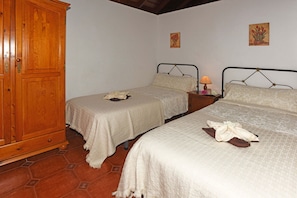 A room with two beds, a wooden wardrobe, and a tiled floor.