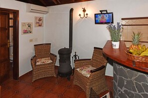 A room with wicker chairs, a stone wall, a fireplace, and a fruit basket.