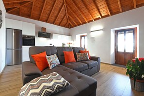 A modern living room with a brown sectional sofa, a small ottoman, and a potted plant. - Casa Spica (Los Llanos de Aridane)