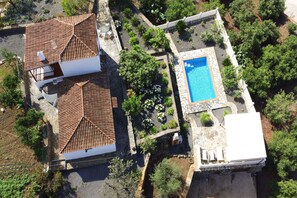 Ein Luftbild eines Anwesens mit einem Haus mit Ziegeldach, einem Swimmingpool und angelegten Gärten.