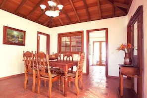 A dining area with a wooden table and chairs, a chandelier, and a painting on the wall.