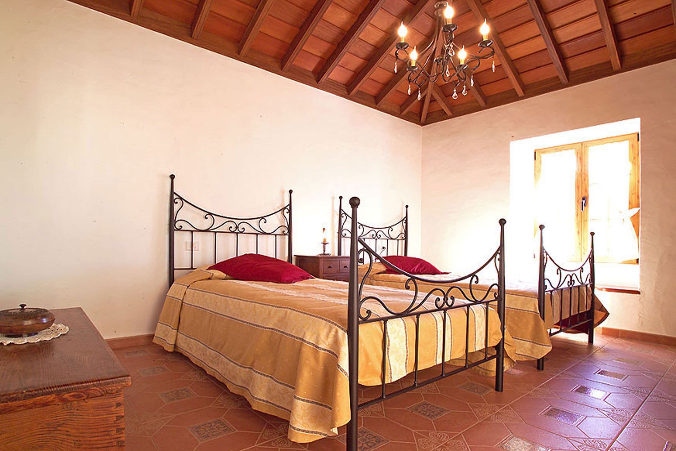 A bedroom with a four-poster bed, a wooden nightstand, and a chandelier.