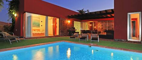 A modern house with a swimming pool, outdoor seating, and a patio area.