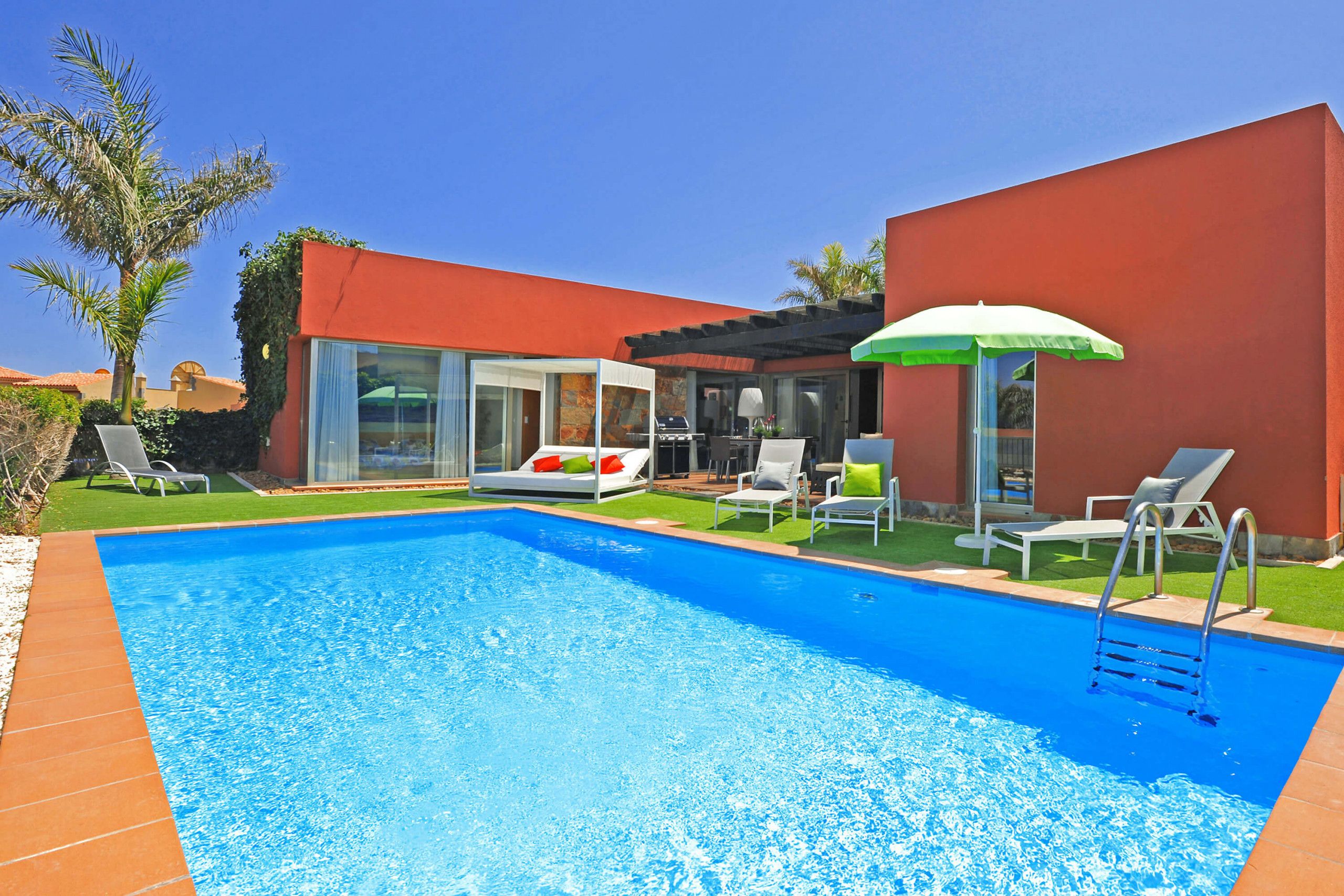 Une piscine à l’eau d’un bleu cristallin, entourée de chaises longues et d’un patio couvert.
