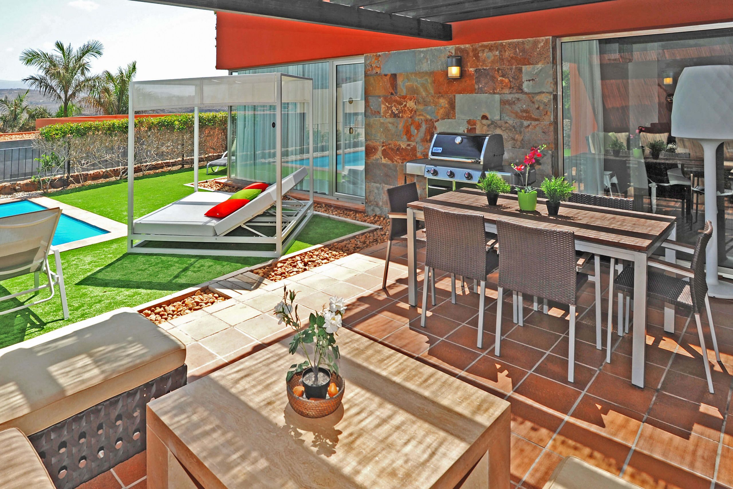 A modern outdoor patio with a barbecue grill, seating area, and a swimming pool.