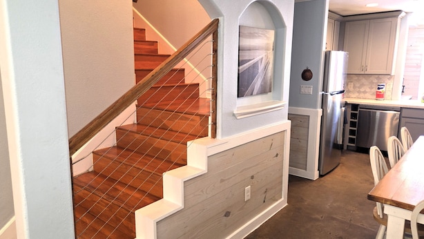 Une cuisine avec un escalier en bois, un réfrigérateur et un coin repas.