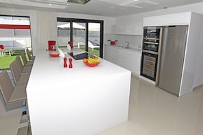 A modern kitchen with a central island, built-in oven, and a large refrigerator.
