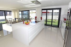 A modern kitchen with a central island, large windows, and a view of the outdoors.