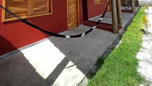 A building with a red facade, wooden doors, and a wooden pergola. - Conforto e Sossego: Chalés à Minutos Da Praia (Prado)