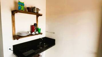 Een minikoelkast, een kookplaat, kookgerei, borden en bestek