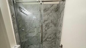 Une salle de bain avec une douche à parois de verre, des toilettes et un meuble-lavabo avec des tiroirs.