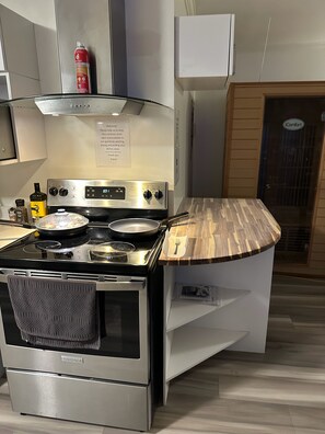 A compact kitchen with a stainless steel stove, a wooden countertop, and a built-in oven.