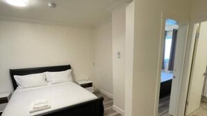 Une chambre à coucher moderne avec un grand lit, une table de chevet et une commode.