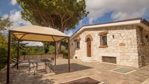 A stone house with a covered patio, a table, and chairs. - Villa Capelvenere (Corbezzolo) (Dorgali)