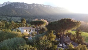 A stone house with a tiled roof surrounded by trees and a mountainous backdrop. - Villa Capelvenere (Corbezzolo) (Dorgali)