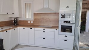 A compact kitchen with white cabinets, a wooden countertop, a Bosch oven, and a coffee maker. - Villa pornic 8/9 persons sea view 1min from the beach (Pornic)
