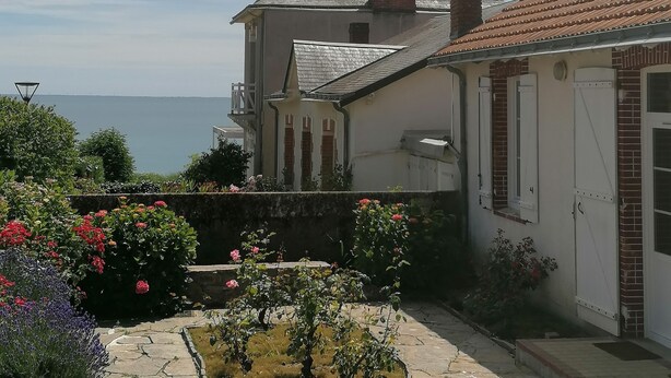 A house with a garden, a view of the sea, and a tiled roof. - Villa pornic 8/9 persons sea view 1min from the beach (Pornic)