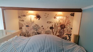 A room with a bed featuring striped bedding, a wall decorated with marine life illustrations, and two wall-mounted lamps. - Villa pornic 8/9 persons sea view 1min from the beach (Pornic)