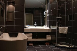 Un baño moderno con bañera, un espejo grande y zona de ducha.