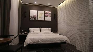 A modern bedroom with a brick accent wall, a large bed, a bedside table, and a wall-mounted artwork.