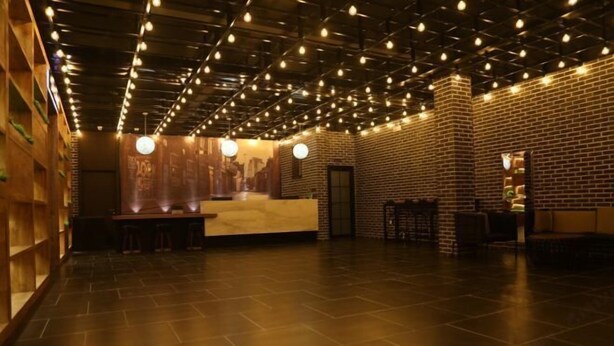 A spacious lobby with a brick wall, a reception desk, and a bar area. - Shou Cheng Hotel Select (Mishan)