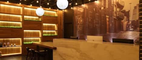A reception area with a marble counter, wooden paneling, hanging lights, and a cityscape mural.