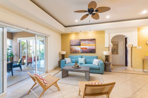 A spacious living room with a blue sofa, a coffee table, and a ceiling fan.