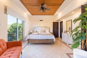 Una camera da letto con un letto, una ventola a soffitto, una grande finestra, un balcone e una pianta.