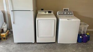 A laundry area with a refrigerator, a washing machine, and a dryer.