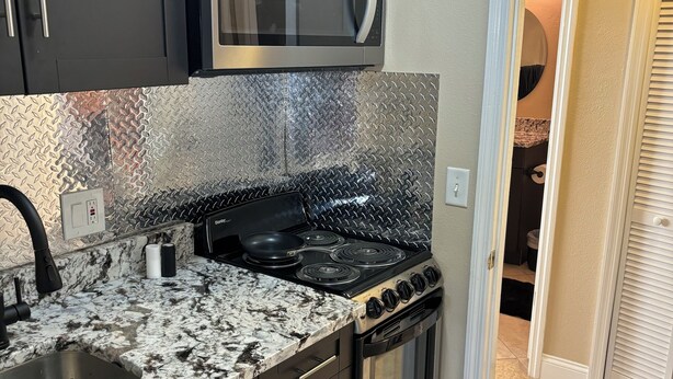 A kitchen with a granite countertop, stainless steel appliances, and dark cabinetry.