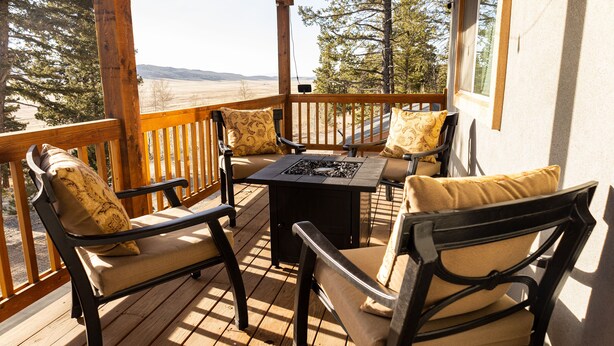 A wooden deck with outdoor furniture, including chairs and a table, overlooking a scenic landscape. - Fully Stocked Family Friendly Cabin Near Breckenridge (Fairplay)
