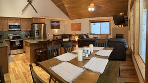 A modern kitchen with stainless steel appliances, a dining area with wooden furniture, and a cozy living room with a leather couch. - Fully Stocked Family Friendly Cabin Near Breckenridge (Fairplay)