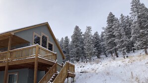 A two-story wooden cabin with a balcony, surrounded by snow-covered trees. - Fully Stocked Family Friendly Cabin Near Breckenridge (Fairplay)