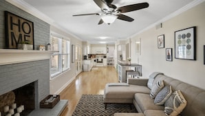A spacious living room with a fireplace, a ceiling fan, and a sofa with decorative pillows.