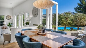 Ein Essbereich mit Holztisch, blau gepolsterten Stühlen und einer Pendelleuchte.