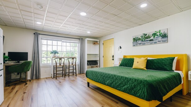Une chambre à coucher avec un lit, un bureau, une chaise et une fenêtre.
