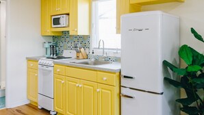 Une cuisine avec des meubles de couleur jaune, un réfrigérateur blanc, un four à micro-ondes et une cuisinière.